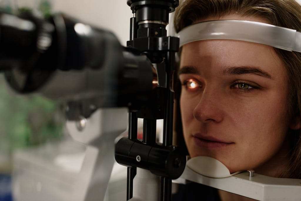 Serious female patient looking at light from contemporary ophthalmic bio microscope while getting eyesight examination in modern clinic during check up